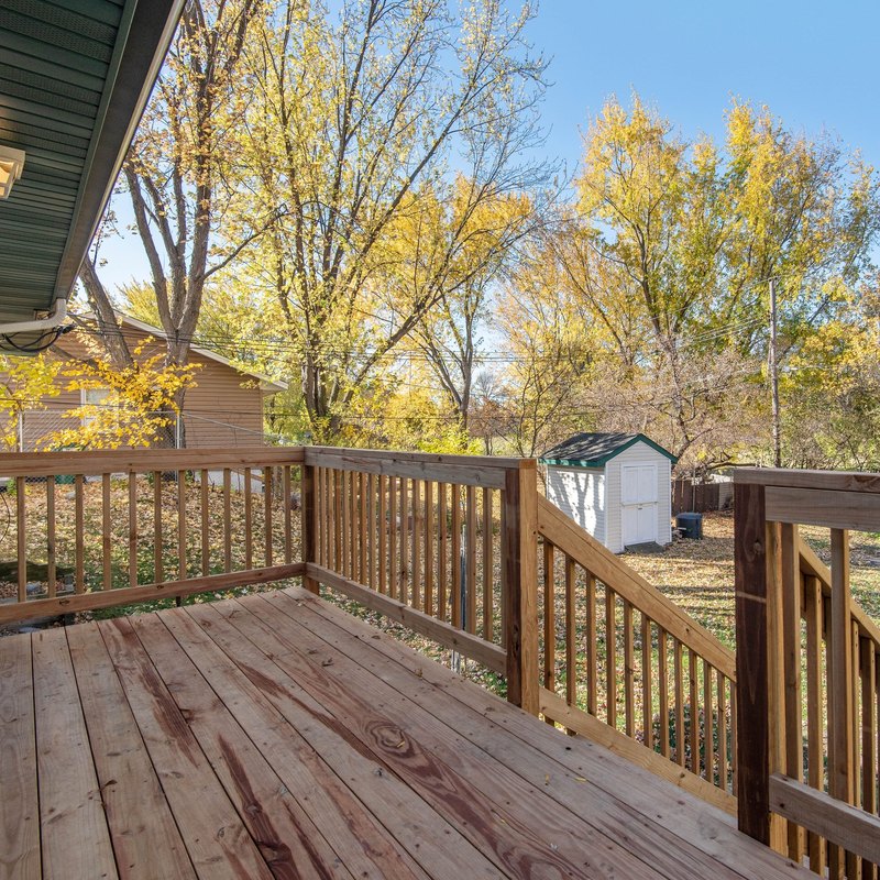 New pressure-treated wood deck with a baluster railing and stairs down to a back yard