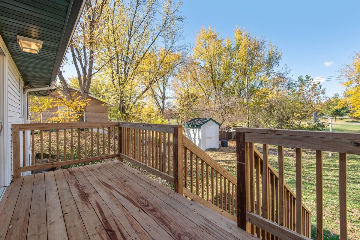New pressure-treated wood deck with a baluster railing and stairs down to a back yard