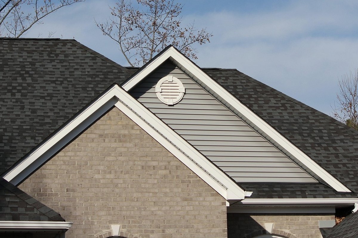 Dark charcoal architectural asphalt shingles on several roof planes above a gray brick gable