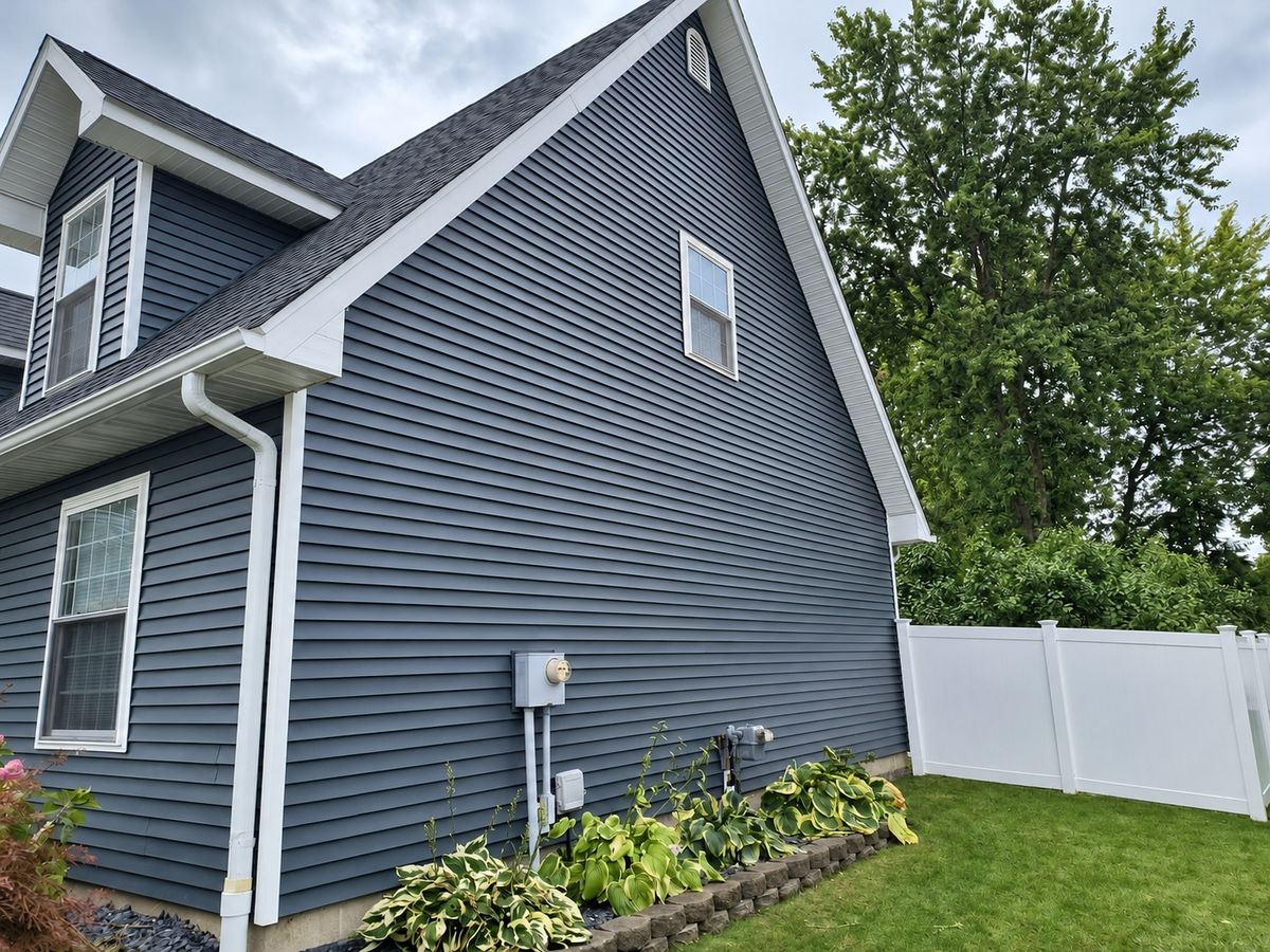 Slate gray vinyl siding on a two-story house gable with a dormer window and white trim