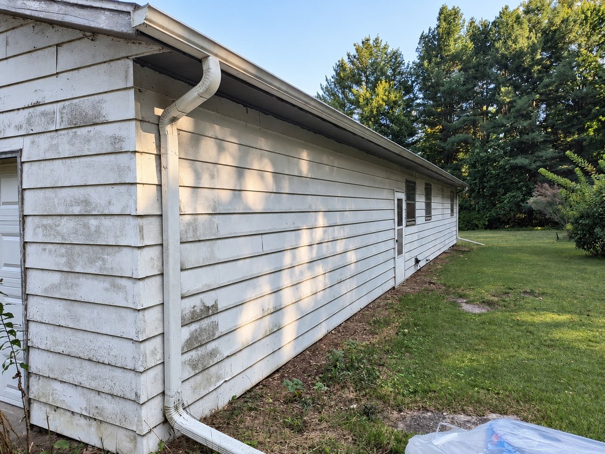 The same house before re-siding, with old white lap siding stained gray-green with mildew